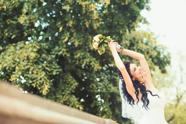 Oldukça mutlu gelin gül buketi ile lüks elbiseli