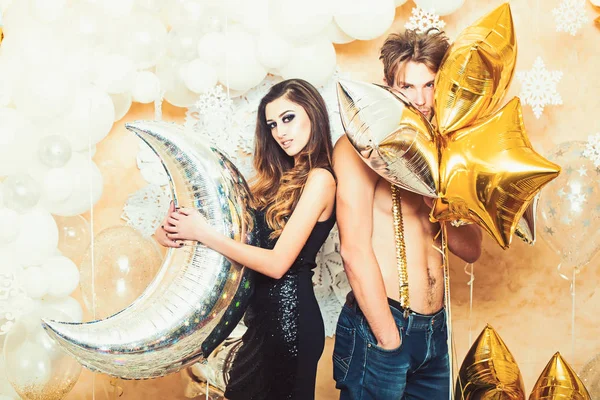 Kvinna och man ler med ballonger vid jul. Flickvän och sexig pojkvän med party ballonger på nyår. Par i kärlek njuta av semester part. Lycklig familj fira jul och nyår — Stockfoto