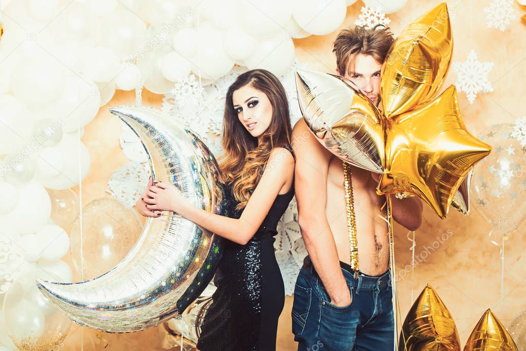 Woman and man smile with balloons at christmas. Girlfriend and sexy boyfriend with party balloons at new year. Couple in love enjoy holiday party. Happy family celebrate christmas and new year