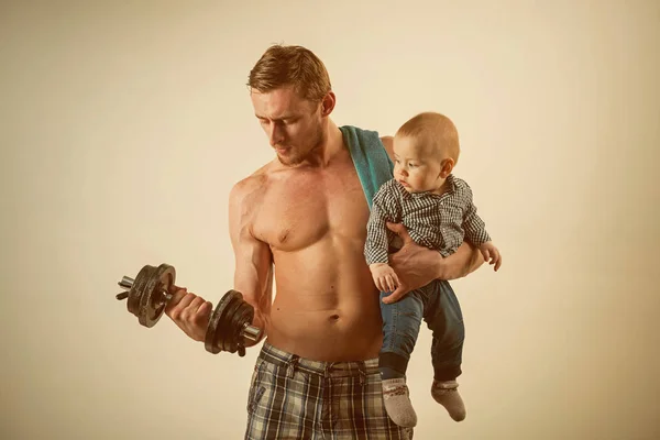 Sport and leisure. Father build biceps triceps with son. Father and child training together. Strong man with dumbbells hold baby boy. Healthy family lifestyle. Active family enjoy sport and fitness