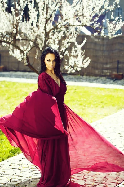 Girl in red dress near blossom