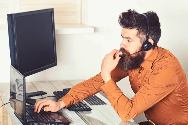 Operadora en línea. Hombre barbudo trabajando en la oficina. Operador de centro de llamadas en el trabajo. Hombre con barba larga y auriculares. Representante de la empresa barbuda con portátil. Responder a las llamadas de los clientes —  Fotos de Stock