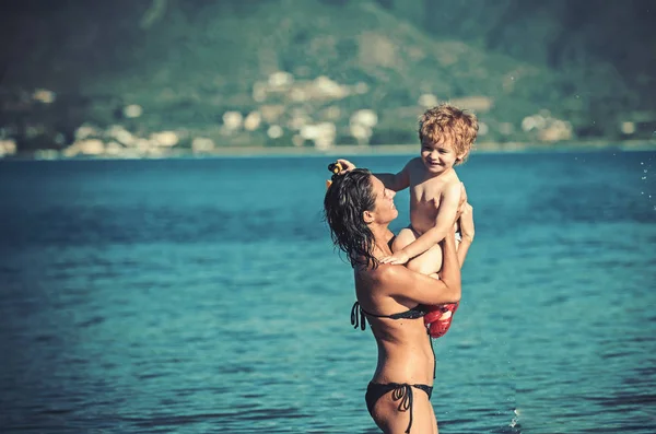 Vacaciones de verano y viajes al océano. madre con hijo nadar en el agua. Familia feliz en el mar Caribe. Maldivas o Miami playa actividad alegría. Las mamás el día la fiesta del chiquitín en las manos de la mujer-padre . — Foto de Stock