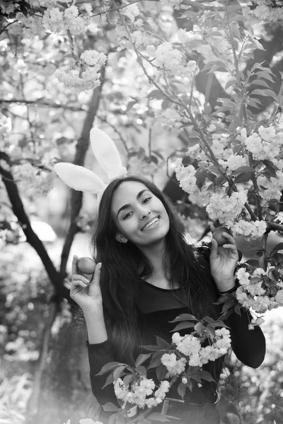 Menina feliz com orelhas de coelho sorrindo com ovos coloridos, sakura — Fotografia de Stock