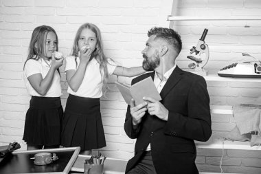 Kız ve baba Kitaplığı'nda okul zamanı. Edebiyat ders ve okuma gramer kitabı. Bilgi gün eğitimde. Öğretmen adam kızlar yeme elma için hikaye okuyun. Geri okul ve ev okullaşma