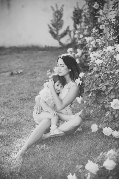 Mom and child relaxing at blossoming rose flowers — Stock Photo, Image