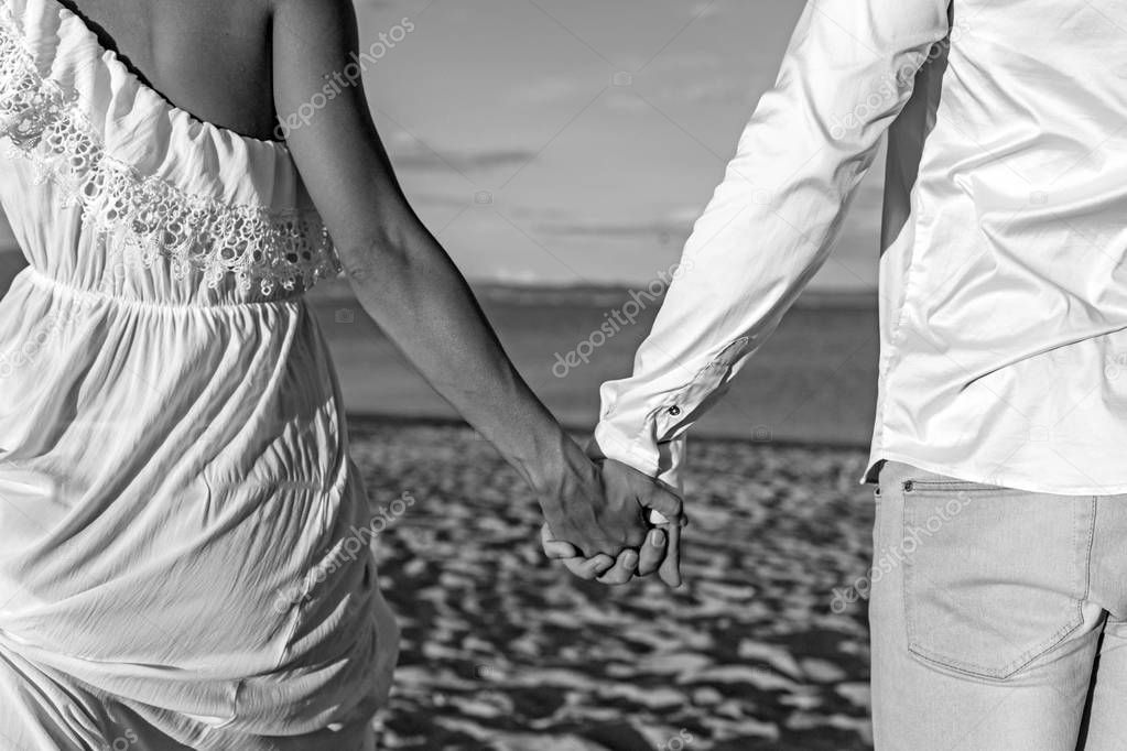 Couple walking in beach holding hands, trust