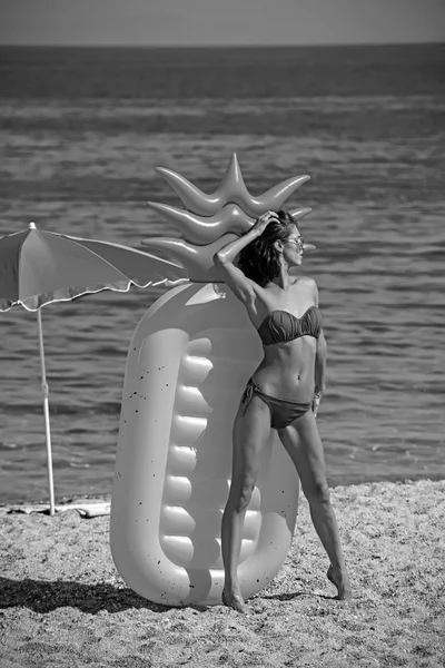 Девушка загорает на пляже с надувным матрасом. девушка в купальнике на солнечном пляже . — стоковое фото