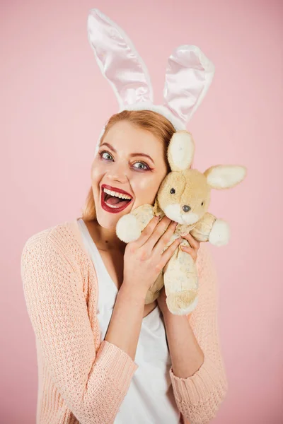 happy woman in bunny ears with toy. Spring holiday. Girl with hare toy. Woman in rabbit bunny ears. Happy easter. Egg hunt. Easter eggs as traditional food. Playful Eater rabbit