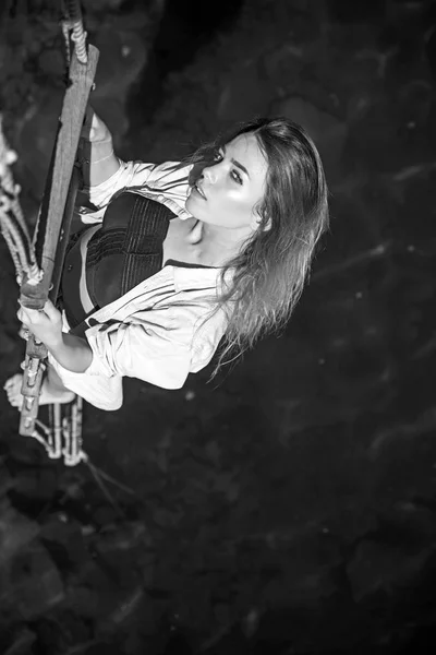 She is entirely dominated by ambition. Pretty woman climb jacobs ladder to the top. Sexy woman climbing up rope ladder. Sensual woman hang on rope over water surface. Achieving her towering ambition — Stock Photo, Image