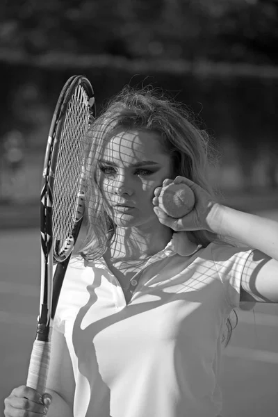 Woman hold racket and ball on lawn. Sensual woman on tennis court. Tennis player training on sunny outdoor. Sportswoman in fashion sportswear on court. Sport activity and wellness concept