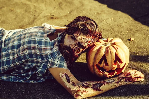 Zombie man lies on pumpkin