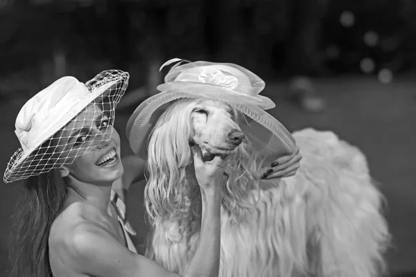 Happy woman and dog in retro hats. Sensual woman smile to funny pet. Fashion girl and domestic animal. Friendship and companionship concept