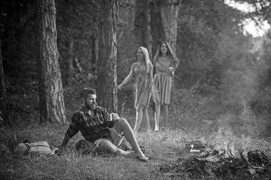 Hipster içecek çay veya kahve, şenlik ateşi ile arka plan bulanık kızlar. Hipster rahatla suratına kamp ateşi ile