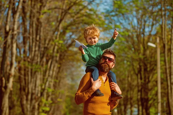 Manche Leute wissen einfach, wie man fliegt. kleiner Junge träumt davon, hoch auf der Schulter seines Vaters zu fliegen. Familie startet Papierflugzeug im Park — Stockfoto