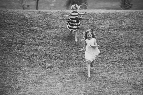 Las niñas corren desde la colina en la hierba verde en el día de verano —  Fotos de Stock