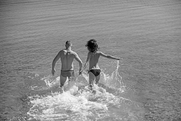 Divertirse, diversión y felicidad de la joven sexy pareja correr y va a nadar en el agua de mar . — Foto de Stock