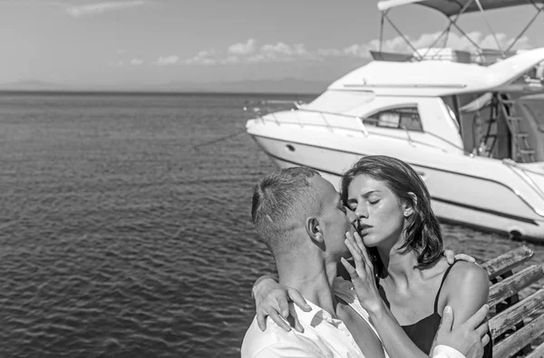 Jovem casal sentado juntos em um banco de mar e beijando . — Fotografia de Stock