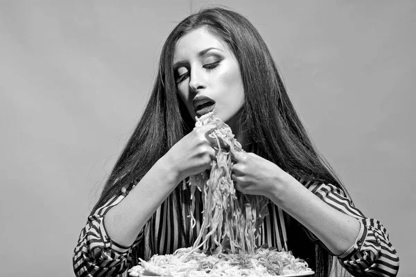 Sexy vrouw eten spaghetti met handen. Vrouw eet pasta schotel met tomatenketchup. Hongerig meisje hebben Italiaanse maaltijd. Schoonheid model met make-up en lang donkerbruine haren hebben diner. Voedsel, voeding en keuken — Stockfoto