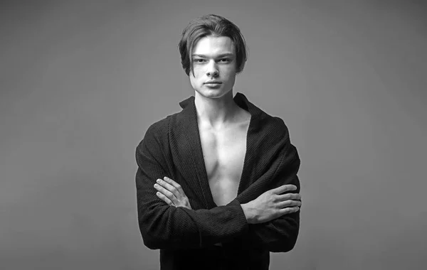 Guy on confident face in black bathrobe holds arms folded, grey background. Macho with stylish long haircut. Masculinity concept. Man with smooth skin on face, neck and chest looking at camera. — Stock Photo, Image