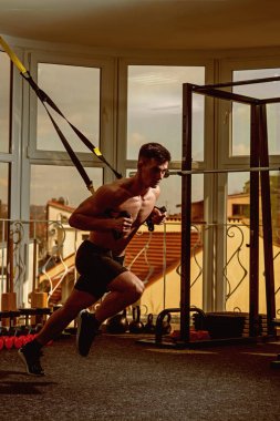Adam çıplak ile gövde ve jimnastik salonu kas göğüs eğitim, trx tadını çıkarın. Sporcu, atlet, kas maço mu egzersiz trx döngüler ile arka plan üstünde pencere. Spor ve spor salonu konsept.