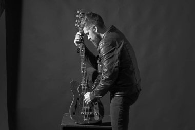 Gri arka plan üzerinde sakallı adam gitar tutar
