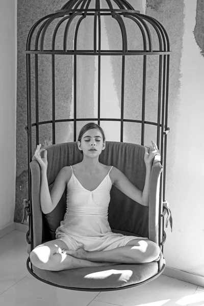 Peaceful and calm. Woman relax in lotus position at home. Pretty woman learn to meditate. Cute woman concentrate and meditate in chair. Practicing meditation to relax. Meditation session