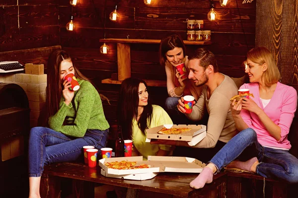 Students, friends, group mates with teacher celebrate, have fun, dark wooden interior background. Youth celebrate with drinks and pizza, spend time together, speaking. Students pizza party concept