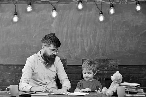 Δάσκαλος και μικρό παιδί κατάρτιση κοινού. Αρσενικό δάσκαλο δείχνει αγόρι πώς να σκιαγραφήσει το χέρι στο χαρτί. Έννοια ατομική εκπαίδευση — Φωτογραφία Αρχείου