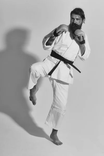 Skäggiga allvarliga karate man i kimono och boxning handskar — Stockfoto