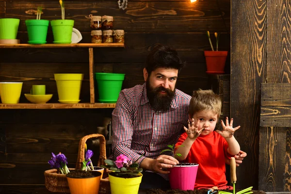 髭の男と小さな男の子は、自然を愛する。花のケアに水をまきます。土壌肥料。家族の日。温室効果。春の花を持つ幸せな庭師。父と息子。自分の仕事について情熱的 — ストック写真