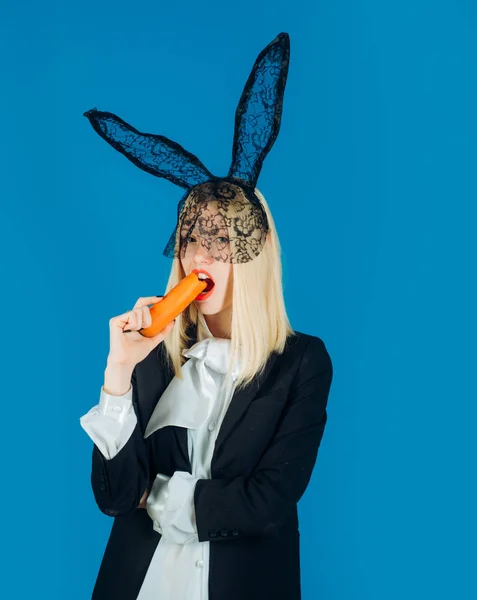 Uma coelhinha gira. Jovem feliz usando orelhas de coelho e tendo ovos de Páscoa. Coelho comer cenoura. — Fotografia de Stock