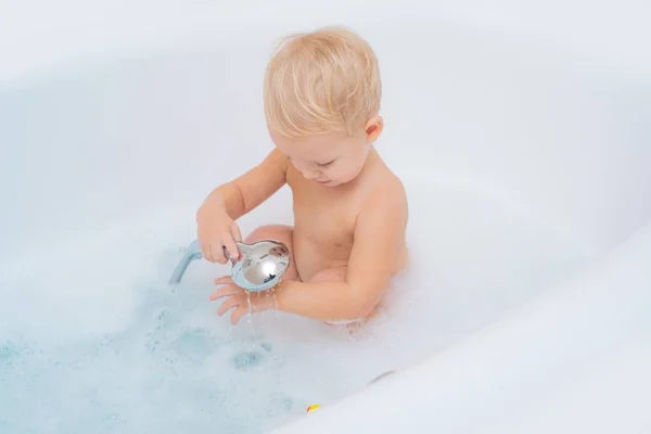 孩子宝宝在白色浴缸里洗澡。孩子在洗澡。快乐的宝宝脸在泡泡浴。快乐的宝宝洗个澡, 玩玩具. — 图库照片