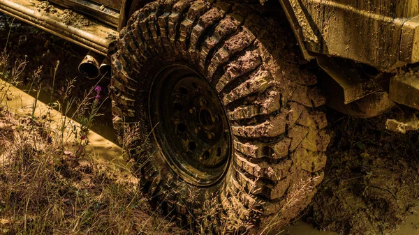 Nejlepší terénní vozidla. Terénní vozidlo jede na horu. Dolní pohled na velké offroad auto kolo na venkovské silnici a hory pozadí. Silniční dobrodružství. Dobrodružné cestování. — Stock fotografie