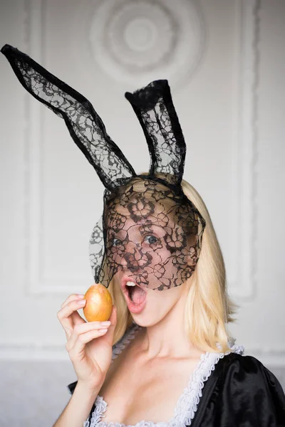 Szép szexi fiatal nő nyuszi fülek gazdaság húsvéti tojás, és úgy néz ki, nagyon érzékien. Meglepetés nő. Kellemes húsvéti ünnepeket. Gyönyörű érzéki szőke. — Stock Fotó