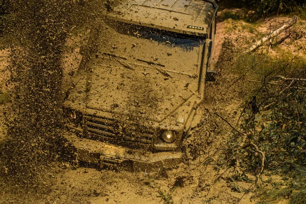 Fango e spruzzi d'acqua nelle corse off-road. Spedizione offroader. I migliori fuoristrada. Veicolo fuoristrada che esce da un buco di fango pericoloso. Tracce su un campo fangoso . — Foto Stock