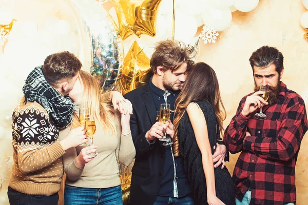Men and women drink champagne, party. Friends celebrate christmas or new year. Couples of lovers kiss. Women and men enjoy party celebration. Christmas and new year holidays — Stock Photo, Image