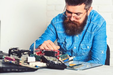 Akıllı profesyonel. Sakallı adam onarım devre kartı. Mühendis veya teknisyen iş başında. Sakallı hippi dijital donanım düzeltmeye çalışır. Assemblying, elektronik cihazların. Yeni teknoloji ve bilim