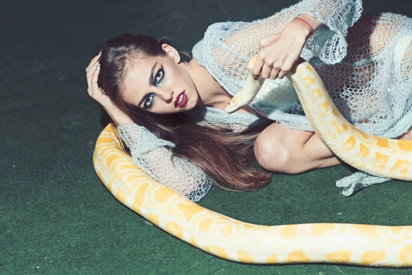 Hermosa mujer morena con pitón albino. Maquillaje de moda, fondo verde —  Fotos de Stock