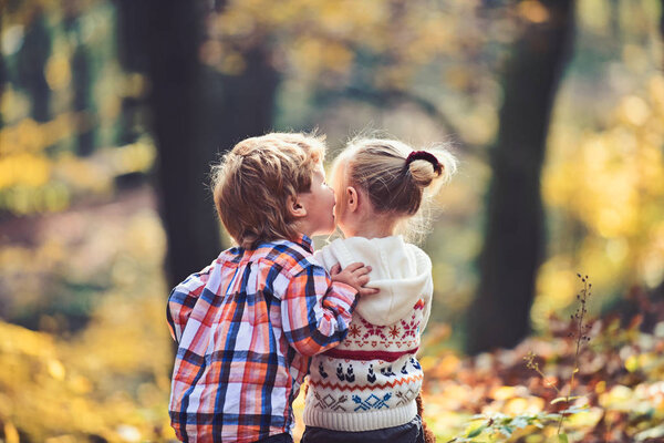 Валентинов мальчик целует маленькую подружку в осеннем лесу. День святого Валентина
