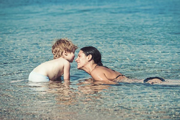 Mothers day holiday of little boy in hands of woman parent. mother with son swim in water. Happy family on Caribbean sea. Summer vacation and travel to ocean. Maldives or Miami beach activity joy.