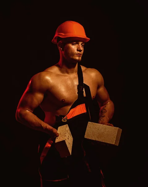 Estamos construyendo sueños. Trabajadora de albañiles. Trabajador de la construcción o constructor en el trabajo en la obra. El trabajador tiene ladrillos en las manos musculosas. Hombre musculoso hace el trabajo de mampostería —  Fotos de Stock