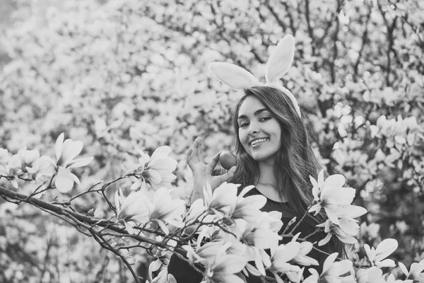 Donna felice sorridente con uovo rosso colorato all'albero di magnolia — Foto Stock