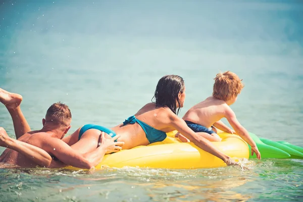 夏休み、海への旅行。カリブの海に幸せな家族カップル。父と息子と母は、水で遊ぶ。パイナップル インフレータブルまたはエアコンのマットレス。モルディブまたはマイアミ ビーチ活動の喜び — ストック写真