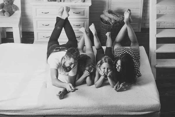 Mutter, Vater und Töchter mit Fernbedienung auf dem Bett liegend — Stockfoto