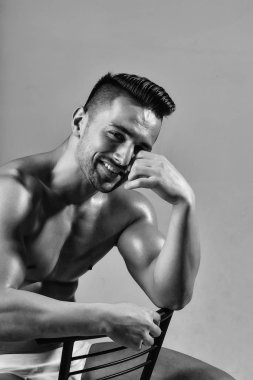 Yakışıklı vücut geliştirmeci sandalyeye oturur