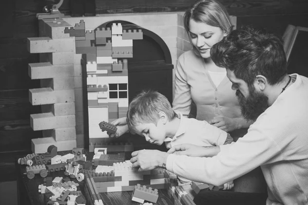 Father, mother and cute son play with constructor bricks. Parent support concept. Family on busy face spend time together in playroom. Kid with parents play with plastic blocks, build construction. — Stock Photo, Image