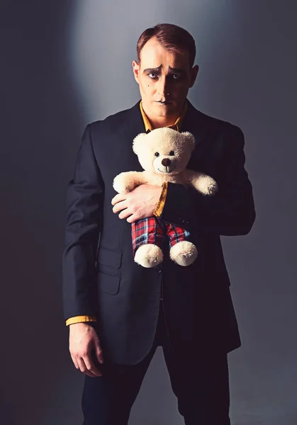Depressed and lonely. Mime man hold teddy bear toy. Stage actor with mime makeup in toy shop. Theatre actor miming sad emotions. Unhappy mime artist. Theatrical performance art and pantomime drama