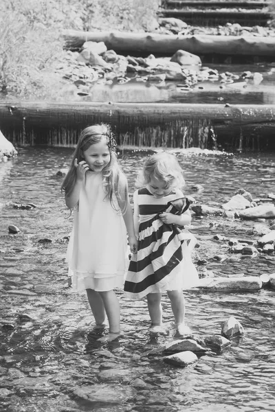 Meninas caminham em pedras na corrente de água na cachoeira — Fotografia de Stock