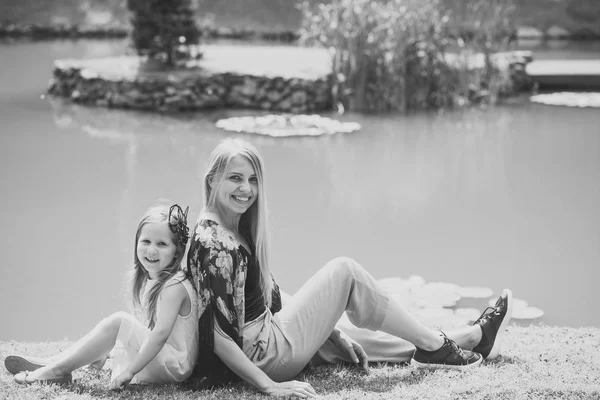 Woman girl sit on grass at pond on sunny day